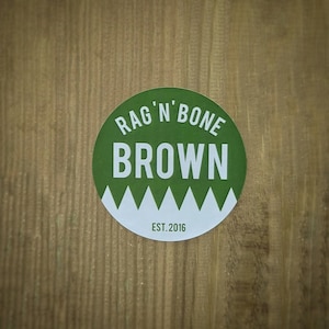 May include: A green circle sticker with white text that reads "Rag 'n' Bone Brown" and "Est. 2016".
