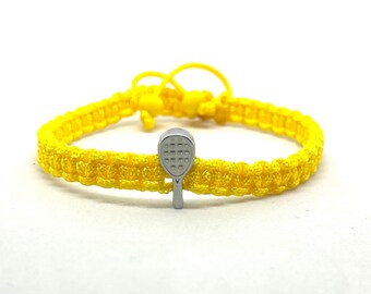 May include: A yellow braided bracelet with a silver paddle charm. The charm is a small, detailed replica of a paddle.