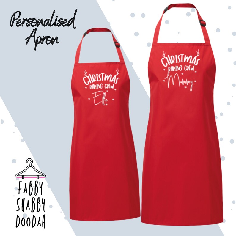 Puede incluir: Dos delantales rojos con texto blanco. Uno dice "Christmas Baking Crew - Effie" y el otro "Christmas Baking Crew - Mommy". Los delantales tienen correas ajustables para el cuello. Arriba est&aacute; el texto "Personalised Apron".