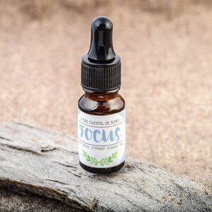 May include: A small brown glass bottle with a black dropper top. The bottle is labelled "Focus" and contains a pure essential oil blend of peppermint, rosemary, and eucalyptus.