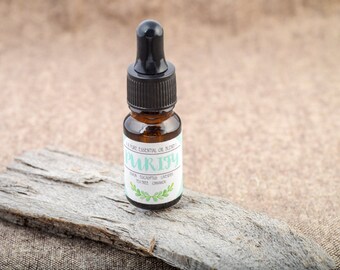 Puede incluir: Una pequeña botella de vidrio marrón con un gotero negro en la parte superior. La botella está etiquetada con "Purify" y enumera los aceites esenciales incluidos: árbol de té, eucalipto, lavanda y naranja.