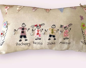 Peut inclure: Coussin rectangulaire beige avec des personnages brodés se tenant la main, chacun avec des vêtements et des boutons uniques. Les noms "Zachary", "Kezia", "Jake" et "Maisie" sont écrits en dessous. Décoré de fleurs en tissu et de fanions.