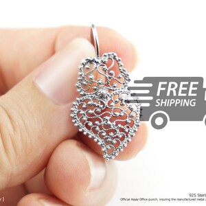 May include: A silver filigree heart-shaped earring with a delicate design. The earring is made of 925 sterling silver and is hallmarked with the official assay office punch.