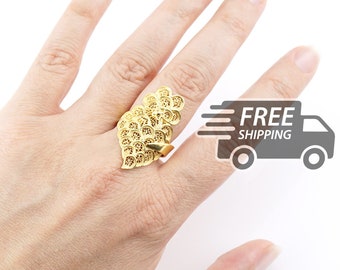 May include: A gold-toned ring featuring an intricate, openwork filigree design composed of multiple overlapping circular and leaf-like patterns. The metalwork displays a delicate, lace-like texture throughout the entire surface of the piece.