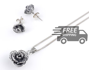May include: A silver jewelry set consisting of a pendant necklace and a pair of stud earrings. Each piece features a detailed rose design crafted with intricate filigree metalwork, showcasing a dark oxidized finish in the recessed areas.