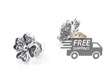 May include: A pair of silver stud earrings shaped like four-leaf clovers. Each earring features an intricate, openwork filigree design within the petals and a smooth, rounded center. The metal has a polished finish with darkened recessed areas.