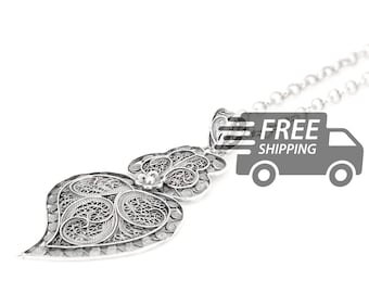 May include: A silver filigree heart pendant necklace featuring intricate wirework patterns. The heart-shaped charm is suspended from a delicate silver chain, showcasing detailed metal loops and swirls that form a complex, openwork design throughout the piece.