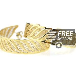 Puede incluir: Un par de pendientes de aro de filigrana dorada con un diseño de hojas. Los pendientes son delicados e intrincados, y serían un hermoso regalo.