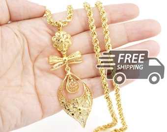May include: A gold-tone necklace featuring a thick rope chain and a pendant composed of a filigree flower, a filigree bow, and a large teardrop-shaped filigree frame containing a smaller teardrop and a flower at the base.