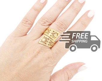 Könnte beinhalten: Ein goldener Ring mit zwei offenen, abgewinkelten rechteckigen Abschnitten, die mit komplizierten Filigran-Drahtmustern verziert sind. Das Metall hat eine polierte Oberfläche und das Design besteht aus sich wiederholenden kreisförmigen Motiven.