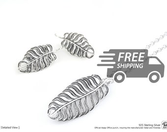 May include: A sterling silver jewelry set consisting of a necklace and a pair of earrings, each featuring a detailed leaf-shaped pendant with an intricate filigree design. The silver metal has a polished finish with darkened recessed areas.