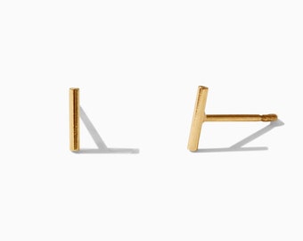 May include: A pair of gold bar stud earrings. The earrings are simple and minimalist, with a straight bar design.