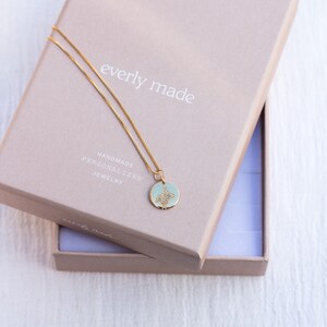 May include: A gold chain necklace with a delicate pendant featuring a floral design. The necklace is in a light brown box with the text "everly made" and "handmade personalized jewelry" printed on it.