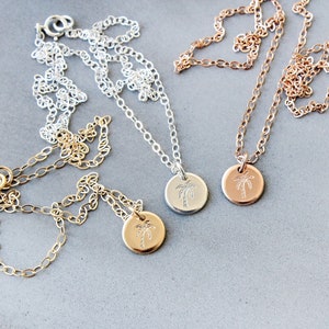 Pu&ograve; includere: Tre delicate collane con ciondoli a forma di palma. Le collane sono in argento, oro e oro rosa.