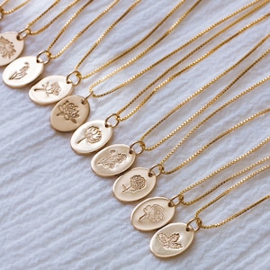 May include: A set of gold chain necklaces with oval pendants featuring different floral designs. Each pendant has a delicate, embossed floral motif.
