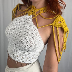 May include: A white crochet top with a yellow crochet halter neckline and shoulder straps. The top has gold beads along the bottom edge and the straps.