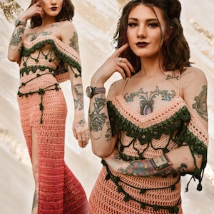 May include: A peach-colored crochet dress with a high slit and a green trim. The dress features a halter top and off-the-shoulder sleeves. The dress is handmade and has a unique, bohemian style.