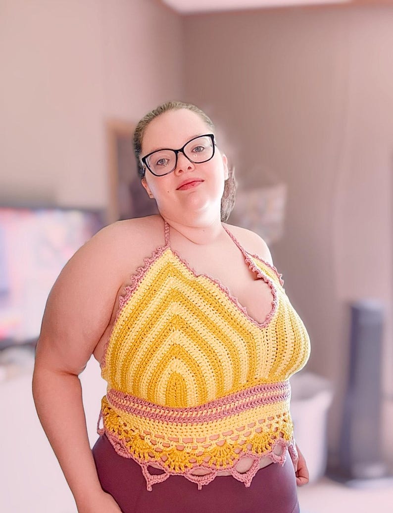 May include: A handmade crochet halter top in yellow and pink. The top features a chevron pattern in yellow and is trimmed with pink crochet. The bottom edge of the top has a scalloped design. The top is worn with burgundy leggings.