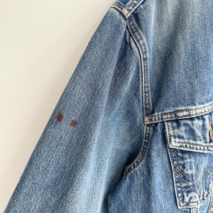 May include: A blue denim jacket with a brown stain on the left sleeve.