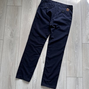 K&ouml;nnte beinhalten: Marineblaue Hose mit klassischem Design. Die Hose hat einen Knopfverschluss, zwei Ges&auml;&szlig;taschen und ein kleines Logo-Patch. Hergestellt aus strapazierf&auml;higem Stoff, ist diese Hose f&uuml;r den t&auml;glichen Gebrauch geeignet.