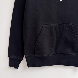 May include: Black hoodie with a kangaroo pocket and ribbed cuffs and hem. The white text "CARHARTT WIP" is printed across the chest. The hoodie is made of a soft, comfortable material.