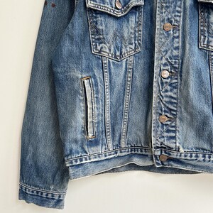 May include: A blue denim jacket with a button closure and a single chest pocket. The jacket has a faded look and is made of a soft, comfortable material.