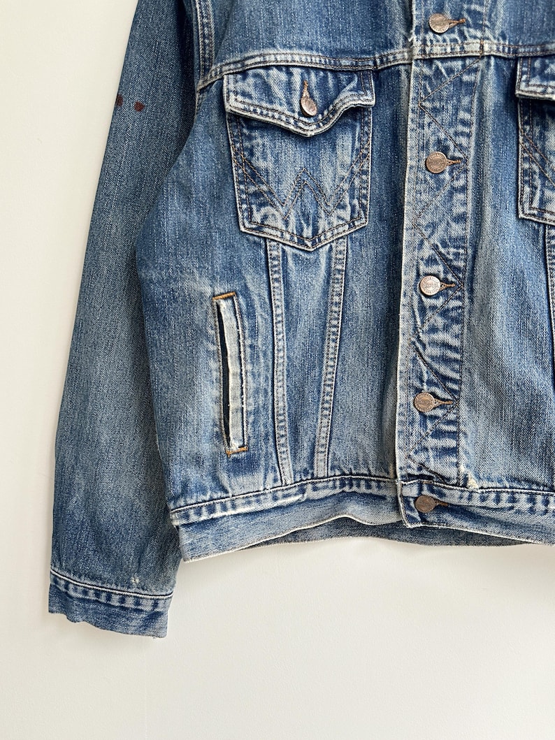 May include: A blue denim jacket with a button closure and a single chest pocket. The jacket has a faded look and is made of a soft, comfortable material.