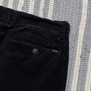 Puede incluir: Pantal&oacute;n de pana negro con un bolsillo trasero y una peque&ntilde;a etiqueta Polo.