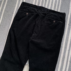 Puede incluir: Pantal&oacute;n de pana negro de pierna recta. El pantal&oacute;n tiene dos bolsillos traseros con cierre de bot&oacute;n.