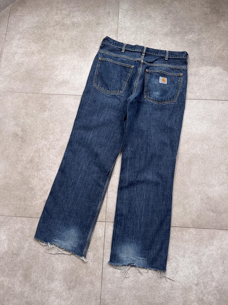 Puede incluir: Vaqueros de mezclilla azul oscuro con un lavado descolorido y dobladillos deshilachados. Los vaqueros presentan un dise&ntilde;o cl&aacute;sico de cinco bolsillos y un peque&ntilde;o parche con el logotipo en el bolsillo trasero. Corte relajado.