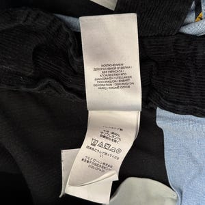 Puede incluir: Una camisa a rayas negras y azules con cuello blanco y una etiqueta blanca con instrucciones de cuidado en varios idiomas. La etiqueta incluye el texto "Исключением декоративной отделки / Без украсата/ &Alpha;&pi;&omicron;&kappa;&lambda;&epsilon;&iota;&sigma;&tau;&iota;&kappa;ή &alpha;&pi;&omicron; &delta;&iota;&alpha;&kappa;ό&sigma;&mu;&eta;&sigma;&eta;/Utelukker Dekorasjon/Enbart Dekoration/Dekorasyon Hari&ccedil; Krome Ozdob".