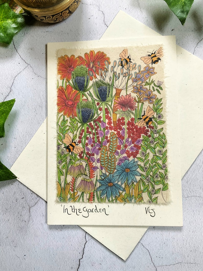 May include: A colorful illustration of a garden scene with flowers, leaves, and bees. The flowers are in shades of red, orange, pink, blue, and yellow. The bees are yellow and black. The text "In the Garden" is written at the bottom of the image.