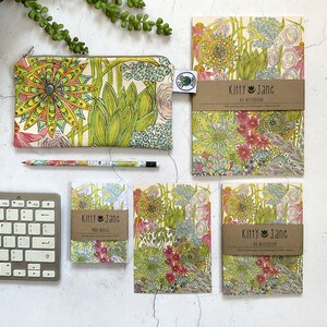 May include: A set of four notebooks and a pencil case featuring a floral pattern with green, pink, and yellow flowers. The notebooks are labelled "Kitty Jane" and are available in A3 and mini sizes.