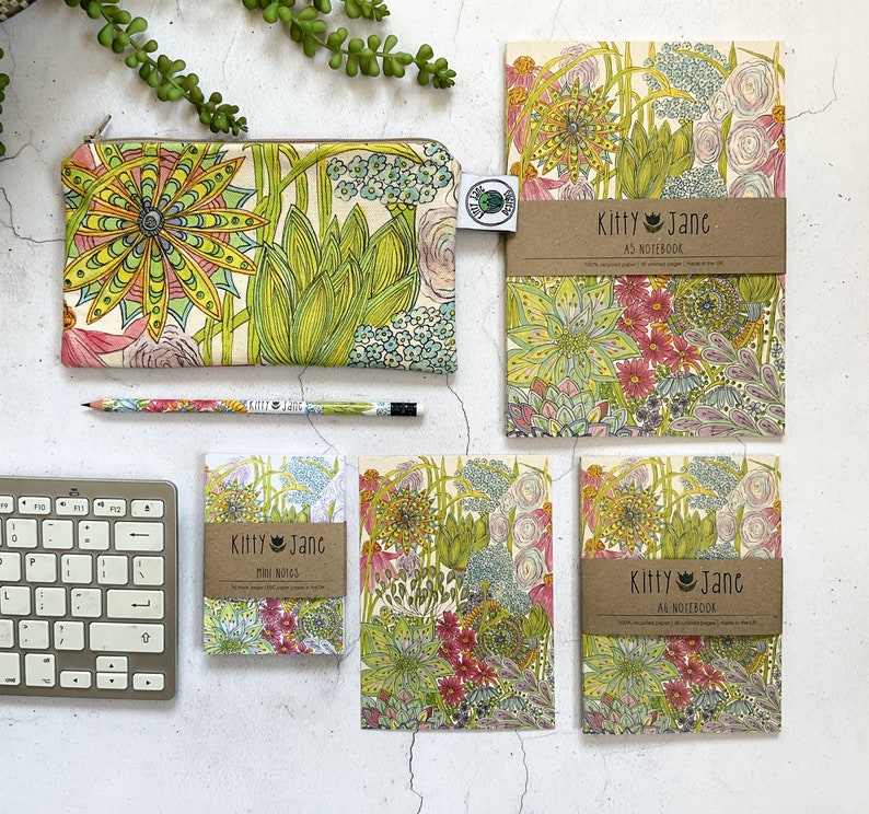 May include: A set of four notebooks and a pencil case featuring a floral pattern with green, pink, and yellow flowers. The notebooks are labelled "Kitty Jane" and are available in A3 and mini sizes.