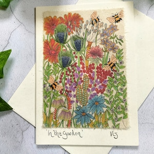 May include: A colorful illustration of a garden scene with flowers, leaves, and bees. The flowers are in shades of red, orange, pink, blue, and yellow. The bees are yellow and black. The text "In the Garden" is written at the bottom of the image.