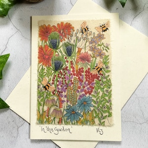 May include: A colorful illustration of a garden scene with flowers, leaves, and bees. The flowers are in shades of red, orange, pink, blue, and purple. The bees are yellow and black. The text 'In the Garden' is written at the bottom of the image.
