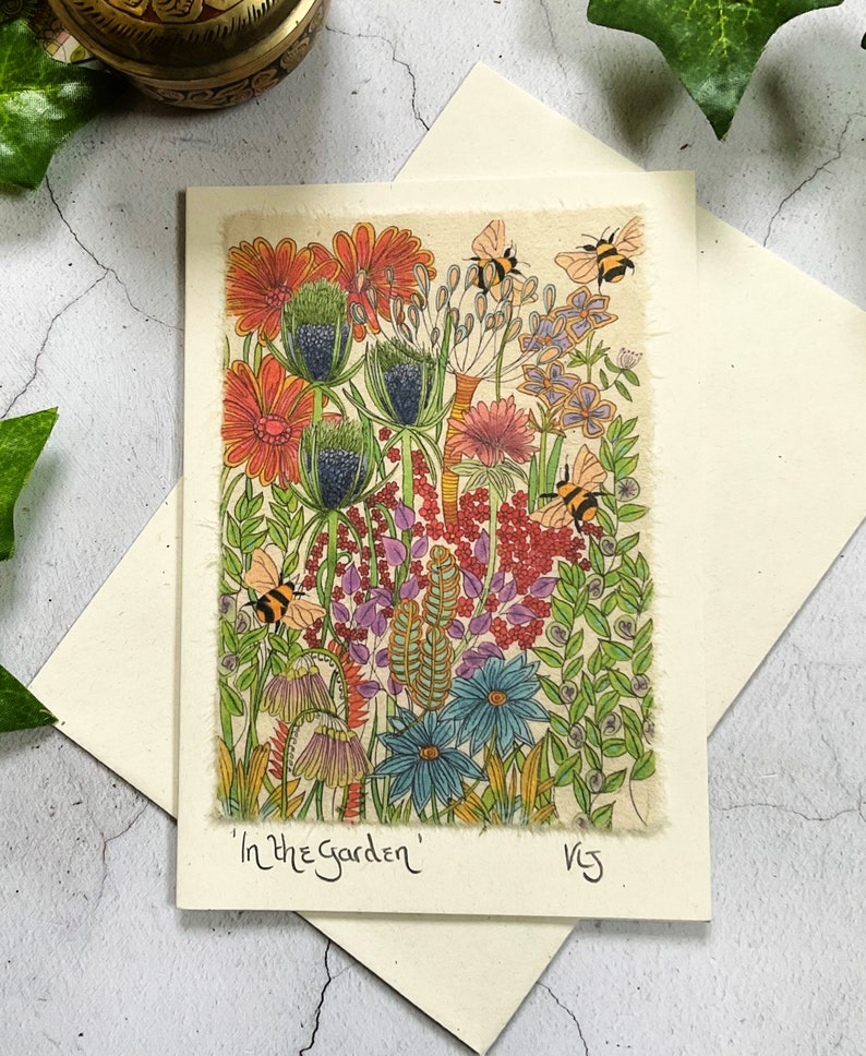 May include: A colorful illustration of a garden scene with flowers, leaves, and bees. The flowers are in shades of red, orange, pink, blue, and purple. The bees are yellow and black. The text 'In the Garden' is written at the bottom of the image.