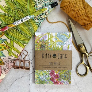 May include: A small notebook with a floral design on the cover. The notebook is labelled "Kitty Jane Mini Notes" and says "50 blank pages | FSC paper | made in the UK".