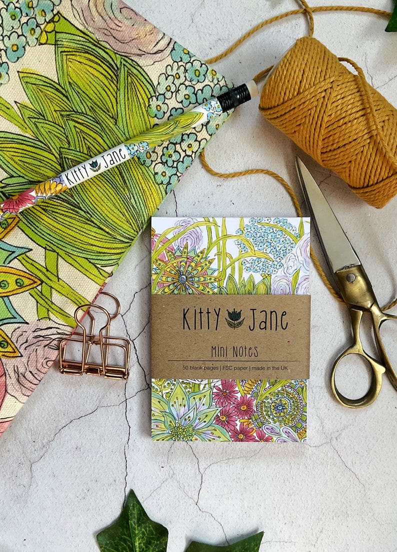 May include: A small notebook with a floral design on the cover. The notebook is labelled "Kitty Jane Mini Notes" and says "50 blank pages | FSC paper | made in the UK".