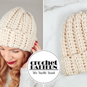 May include: A crocheted beanie hat in a cream color. The hat is made with a textured stitch and has a folded brim. The hat is lying on a white marble surface. The text "crochet pattern" is visible in a black circle.
