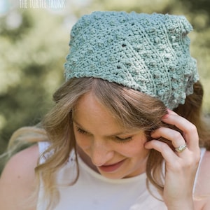 Puede incluir: Una mujer lleva una diadema de crochet verde claro con un patr&oacute;n texturizado. La diadema est&aacute; atada en la parte posterior de su cabeza. Lleva un top blanco sin mangas y tiene un tatuaje en la mu&ntilde;eca que dice "imagine".