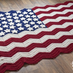 May include: A crocheted American flag blanket with red, white, and blue yarn. The blanket features a blue field with white stars and red and white stripes.