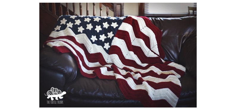 May include: A crocheted American flag blanket in red, white, and blue, draped over a brown leather couch.