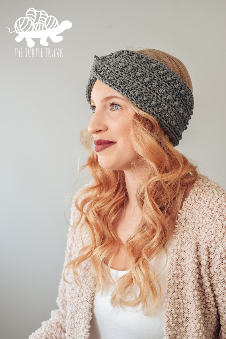 May include: A gray crocheted headband with a twisted design. The headband is worn by a person with long, blonde hair.