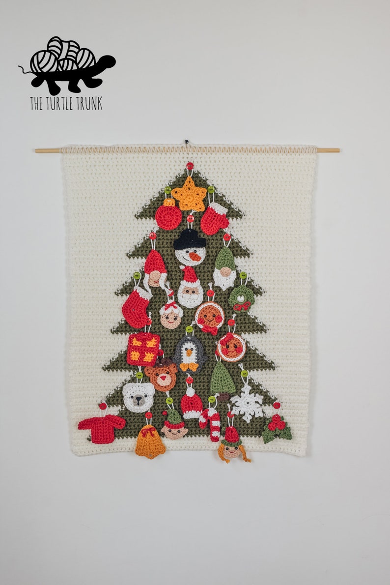 Puede incluir: Un tapiz de &aacute;rbol de Navidad tejido a crochet con fondo blanco y &aacute;rbol verde. El &aacute;rbol est&aacute; decorado con 20 adornos tejidos a crochet de colores, incluyendo un mu&ntilde;eco de nieve, un ping&uuml;ino, un oso, una media, una estrella y un hombre de jengibre. El texto "THE TURTLE TRUNK" est&aacute; en la parte superior de la imagen.