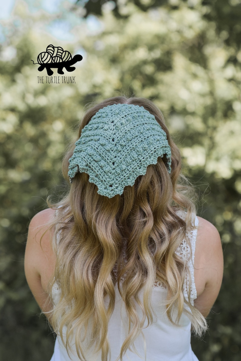 Puede incluir: Una diadema de crochet de color verde claro con un borde festoneado. La diadema la lleva puesta una persona con el pelo largo y ondulado de color rubio.