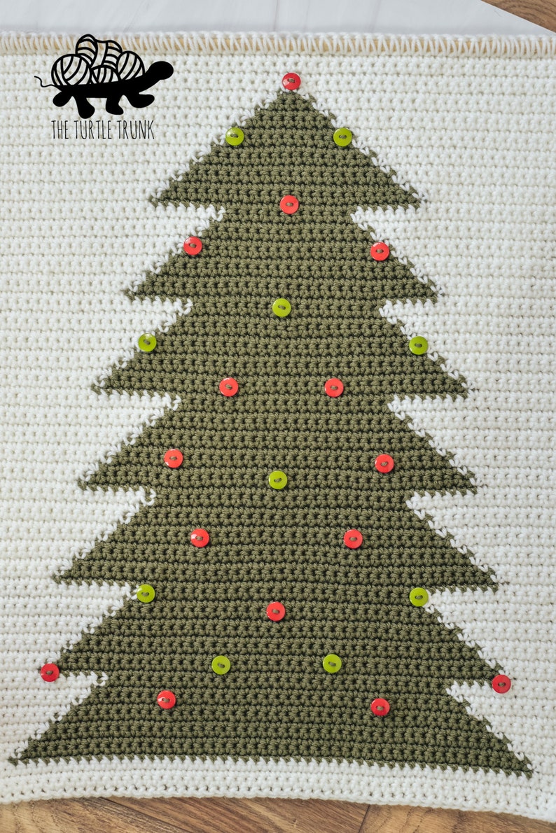 Puede incluir: Una manta de &aacute;rbol de Navidad tejida a crochet con un &aacute;rbol verde y fondo blanco. El &aacute;rbol est&aacute; decorado con botones rojos y verdes.