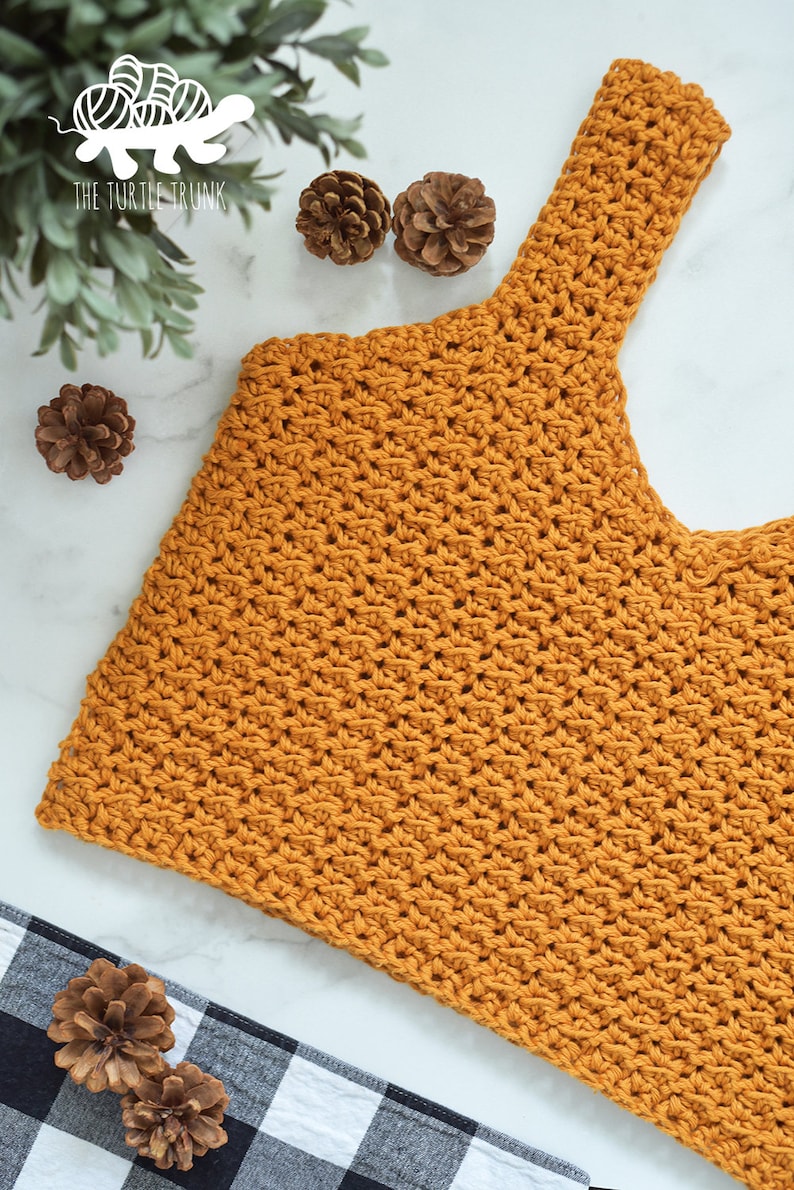 May include: A mustard yellow crochet top with a wide, scoop neck and thin straps. The top is made with a textured stitch and has a cropped length.