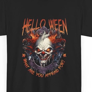 Könnte beinhalten: Ein schwarzes T-Shirt mit einer Grafik eines finsteren Clown-Gesichts mit leuchtend orangefarbenen Augen und rotem Haar, eingerahmt von einem dunklen, verzierten Spiegel. Der Text HELLO WEEN und WHAT ARE YOU AFFRAID FOR? ist in Orange aufgedruckt.