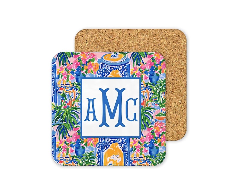 a square coaster with a vibrant floral pattern and a monogrammed logo.